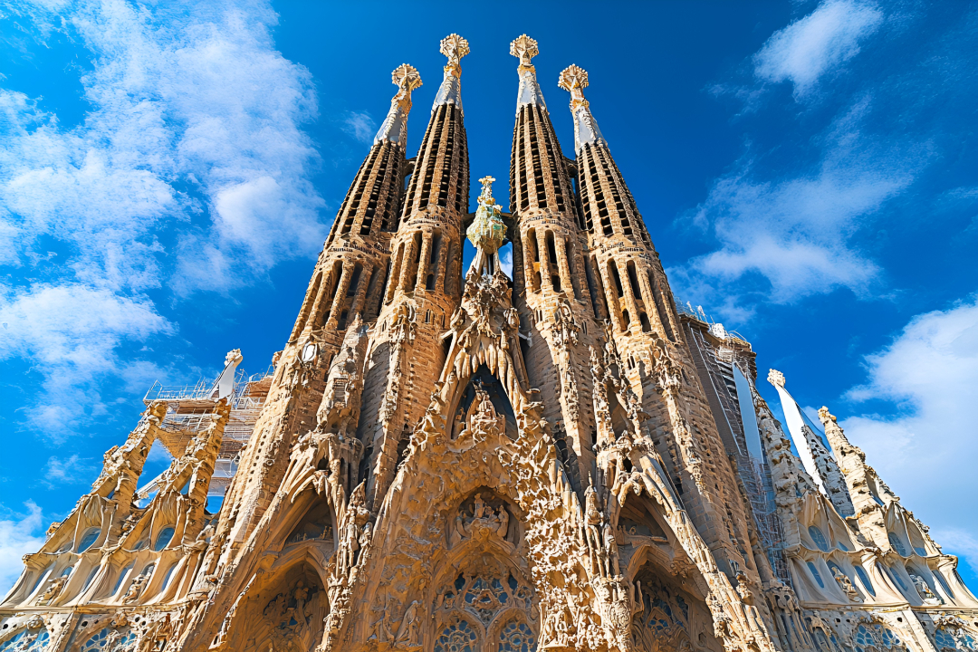 8k超清照片，现代建筑设计风格，西班牙巴塞罗那的圣家堂（Sagrada Familia），主色调为蓝色、白色和棕色，蓝天白云下，建筑物由多个尖塔组成，尖塔顶部有金色装饰，正面装饰有复杂的雕刻和图案，展（商业使用）.jpg